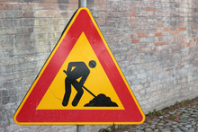Warning sign showing man digging hole.