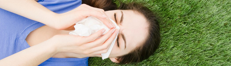 Woman lying on grass sneezing. Woman lying on grass sneezing.